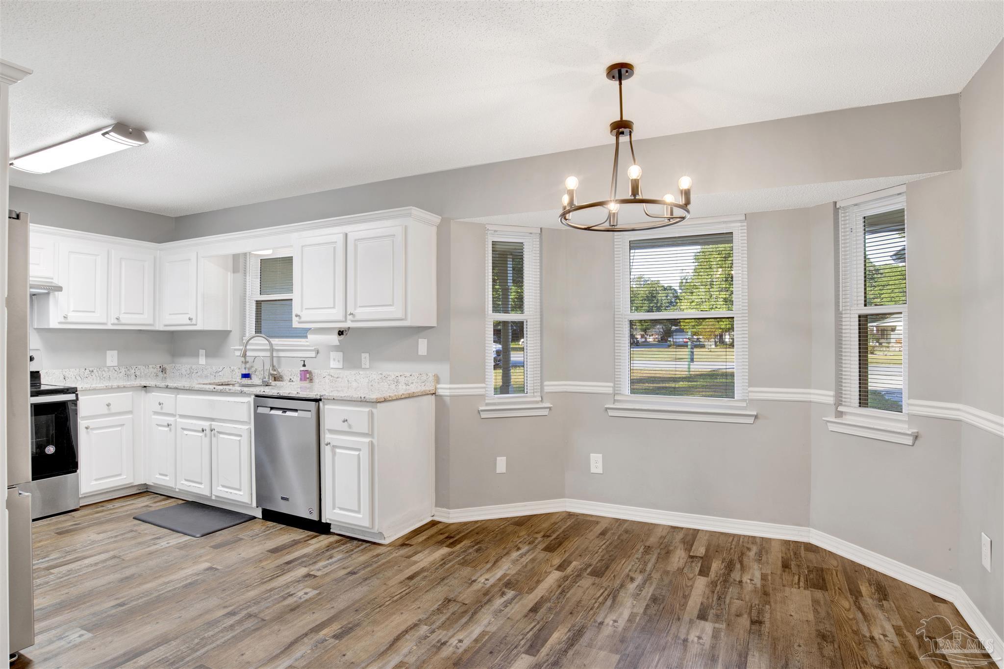 5801 Loring Drive Milton, FL 32583 - Photo 6 of 27 a kitchen that has a lot of white cabinets and wooden floor