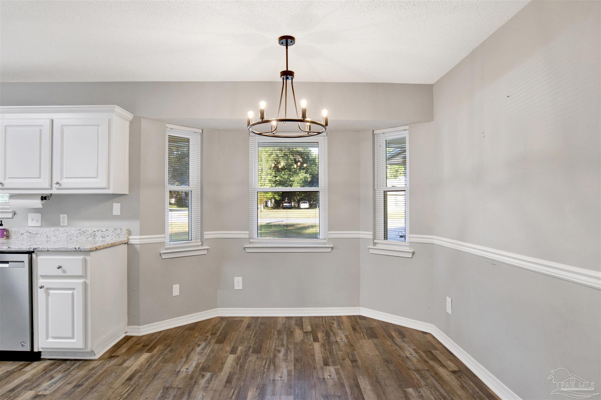 5801 Loring Drive Milton, FL 32583 - Photo 7 of 27 a kitchen with granite countertop white cabinets and wooden floor