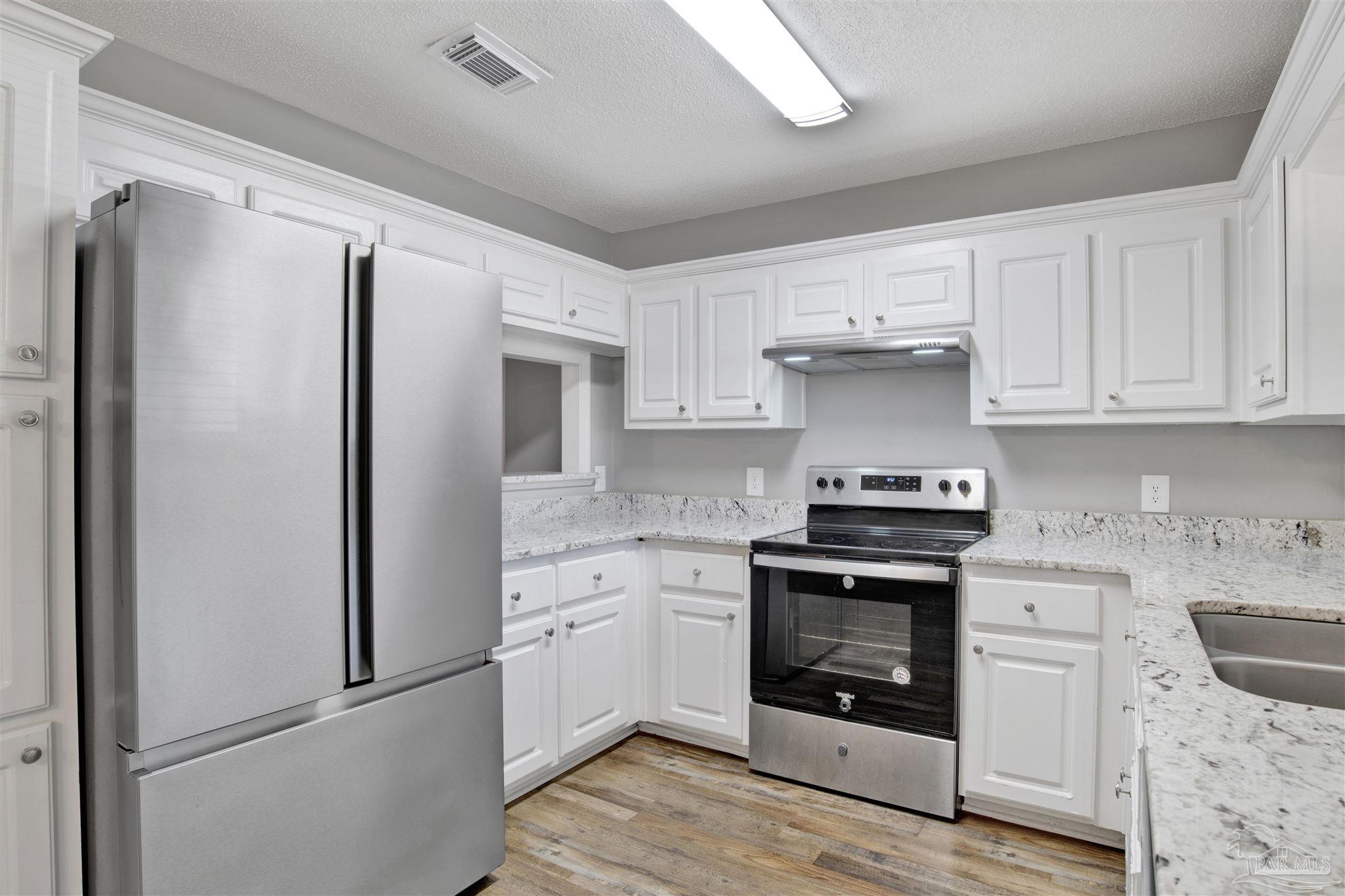 5801 Loring Drive Milton, FL 32583 - Photo 9 of 27 a kitchen with white cabinets and stainless steel appliances