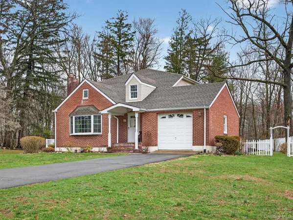 a front view of a house with a garden and trees