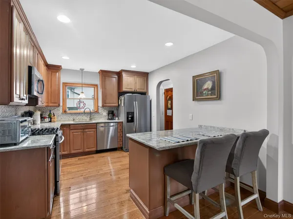 a kitchen with stainless steel appliances granite countertop a table chairs sink refrigerator and cabinets
