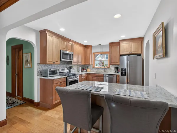 a kitchen with stainless steel appliances granite countertop a refrigerator a stove a sink a dining table and chairs