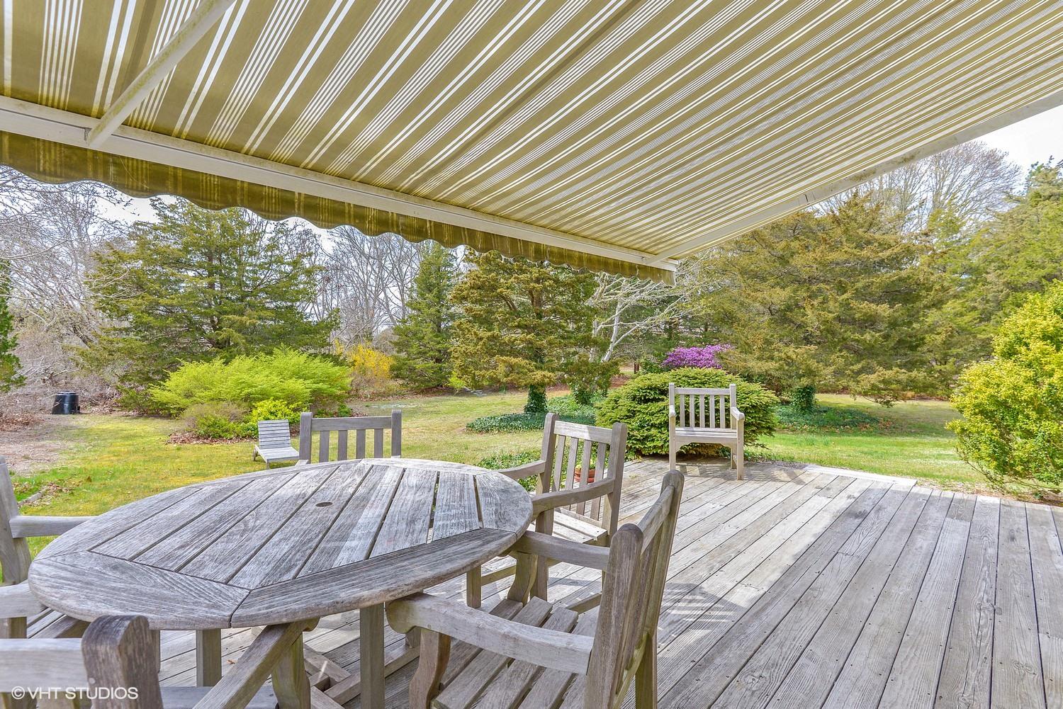 2055 Bridge Road Eastham, MA 02642 - Photo 16 of 22 a view of a patio with table and chairs under an umbrella with a small yard