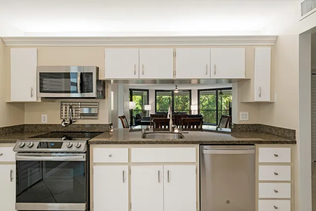 a kitchen with stainless steel appliances granite countertop a stove a sink and a white cabinets