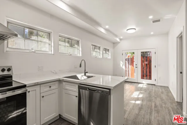 a kitchen with a sink dishwasher and a stove with wooden floor