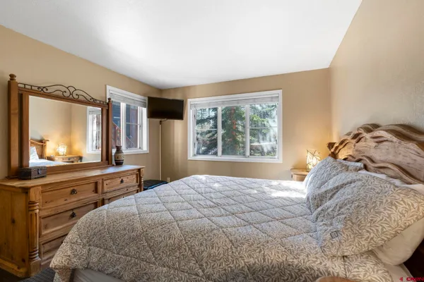 a bedroom with a large bed and a flat tv screen on dresser