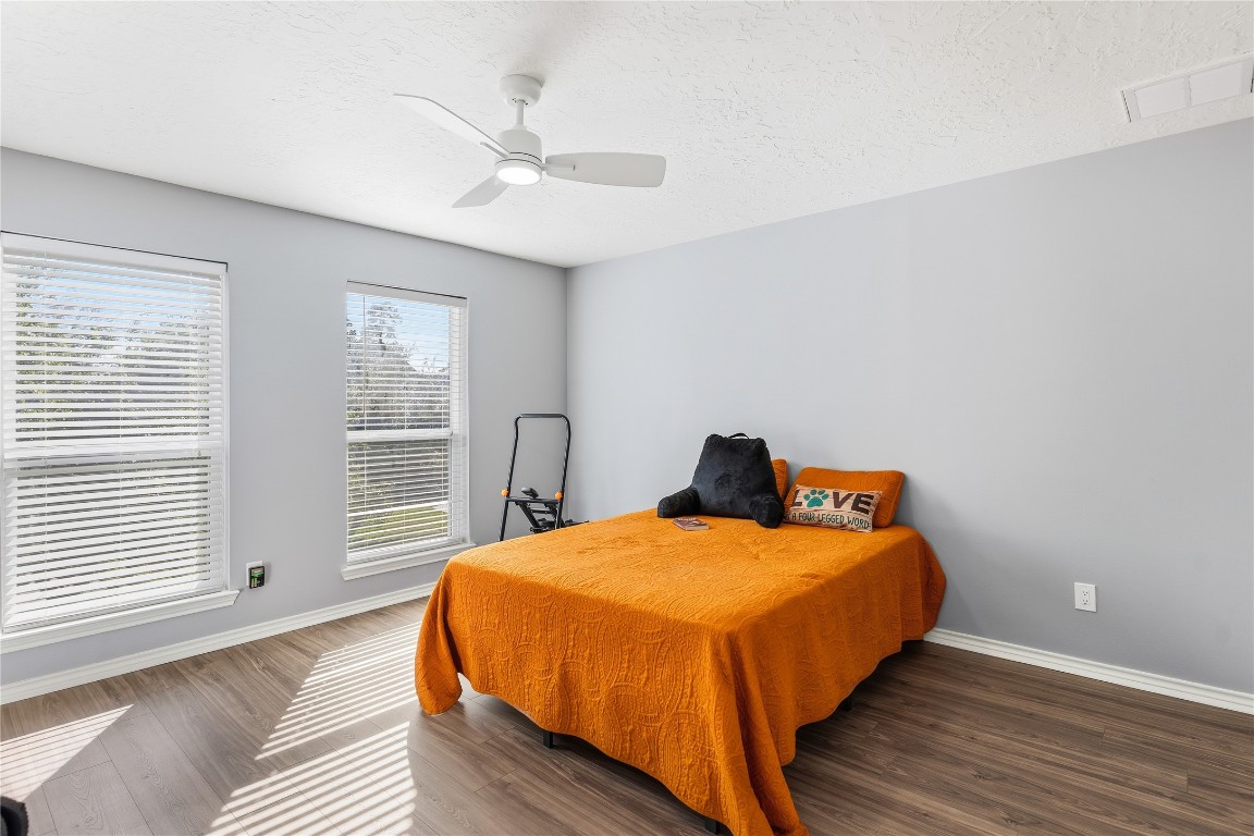 6618 Wimbledon Trail Road Spring, TX 77379 - Photo 27 of 43 Bright bedroom with two large windows, wood flooring, and a ceiling fan.