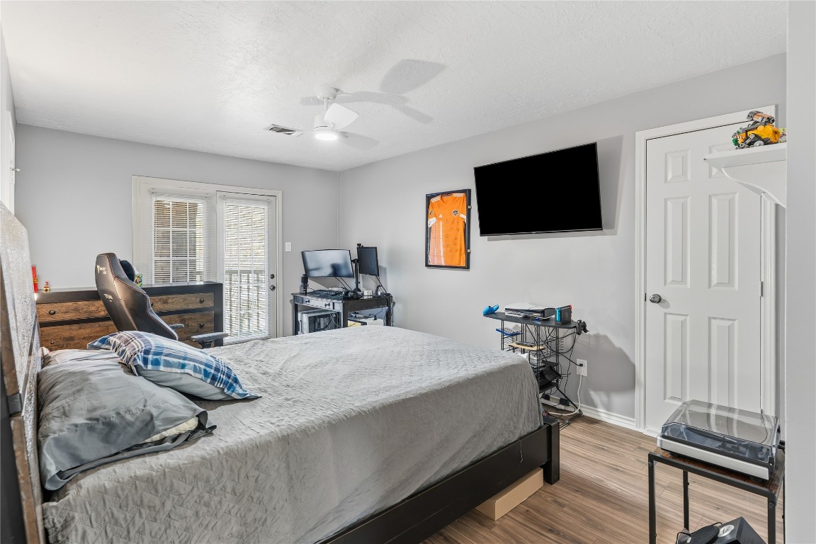 6618 Wimbledon Trail Road Spring, TX 77379 - Photo 30 of 43 This bedroom offers a modern yet cozy retreat centered around a spacious bed. Wood-style flooring adds warmth, while a ceiling fan enhances comfort. French doors open to a private balcony, filling the room with natural light and providing seamless access to the outdoors.