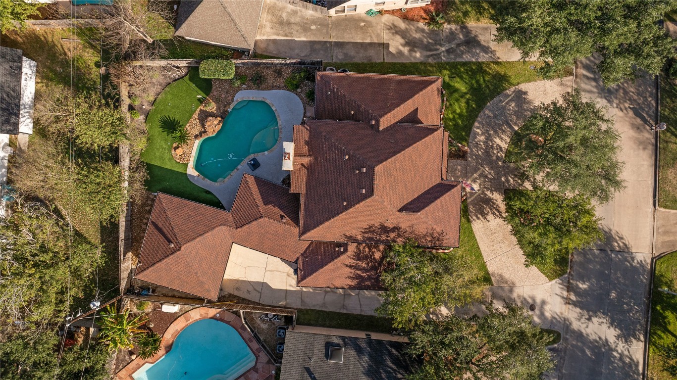 6618 Wimbledon Trail Road Spring, TX 77379 - Photo 40 of 43 This aerial view showcases a spacious home with a red-tiled roof, featuring a lush backyard with a pool and well-maintained landscaping. It's situated on a corner lot with a circular driveway and surrounded by mature trees, offering privacy and curb appeal.