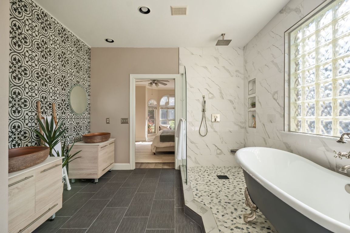8101 Red Bird Court Austin, TX 78726 - Photo 22 of 33 a spacious bathroom with a granite countertop tub sink a mirror a shower and a bathtub
