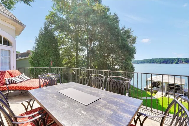 a kitchen with stainless steel appliances granite countertop a refrigerator a sink dishwasher a stove and a dining table with wooden floor