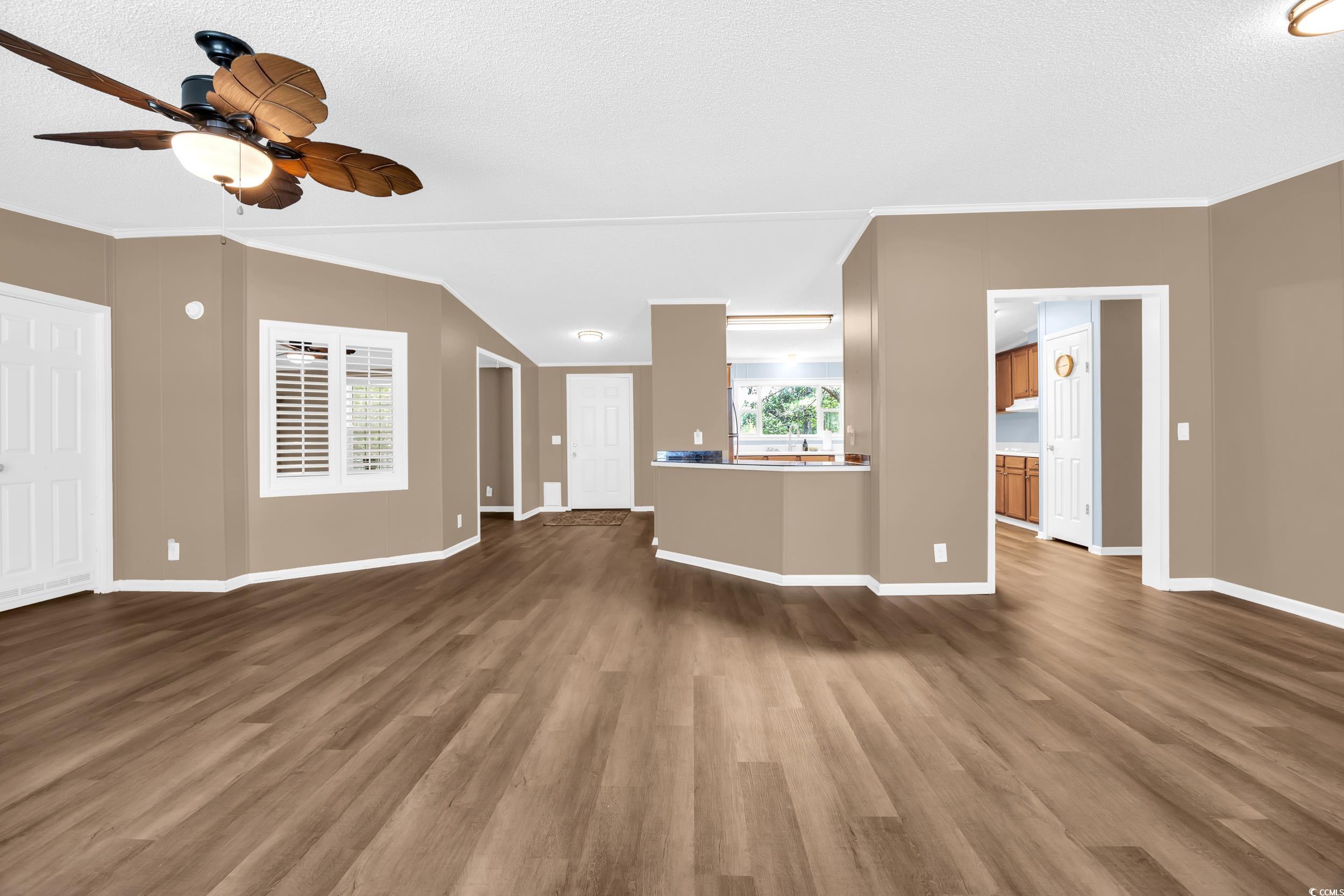 3373 Lake Pond Road Loris, SC 29569 - Photo 11 of 33 Unfurnished living room featuring dark wood-style flooring, a ceiling fan, a textured ceiling, and ornamental molding