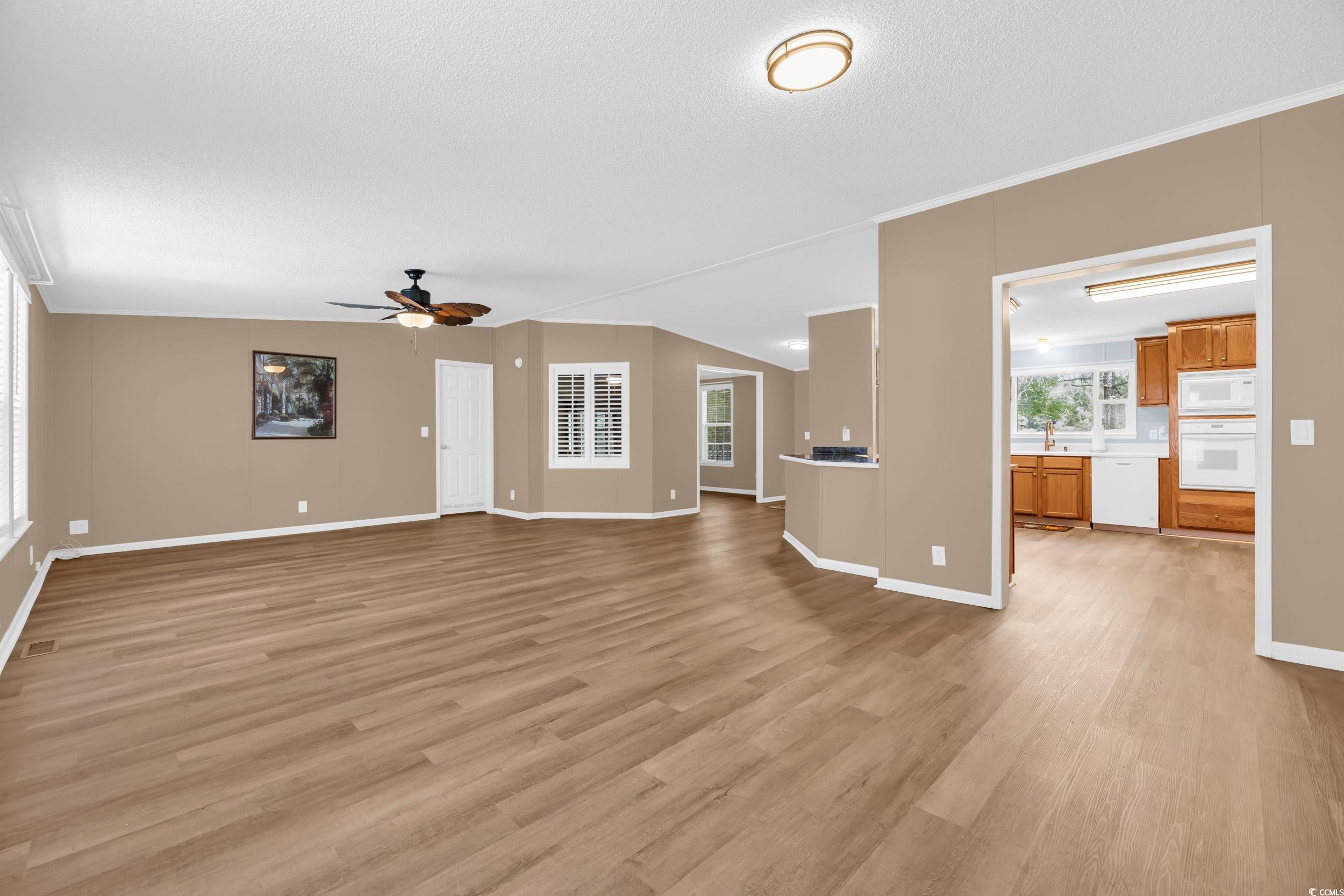 3373 Lake Pond Road Loris, SC 29569 - Photo 12 of 33 Unfurnished living room featuring a ceiling fan, light wood-type flooring, a textured ceiling, and ornamental molding