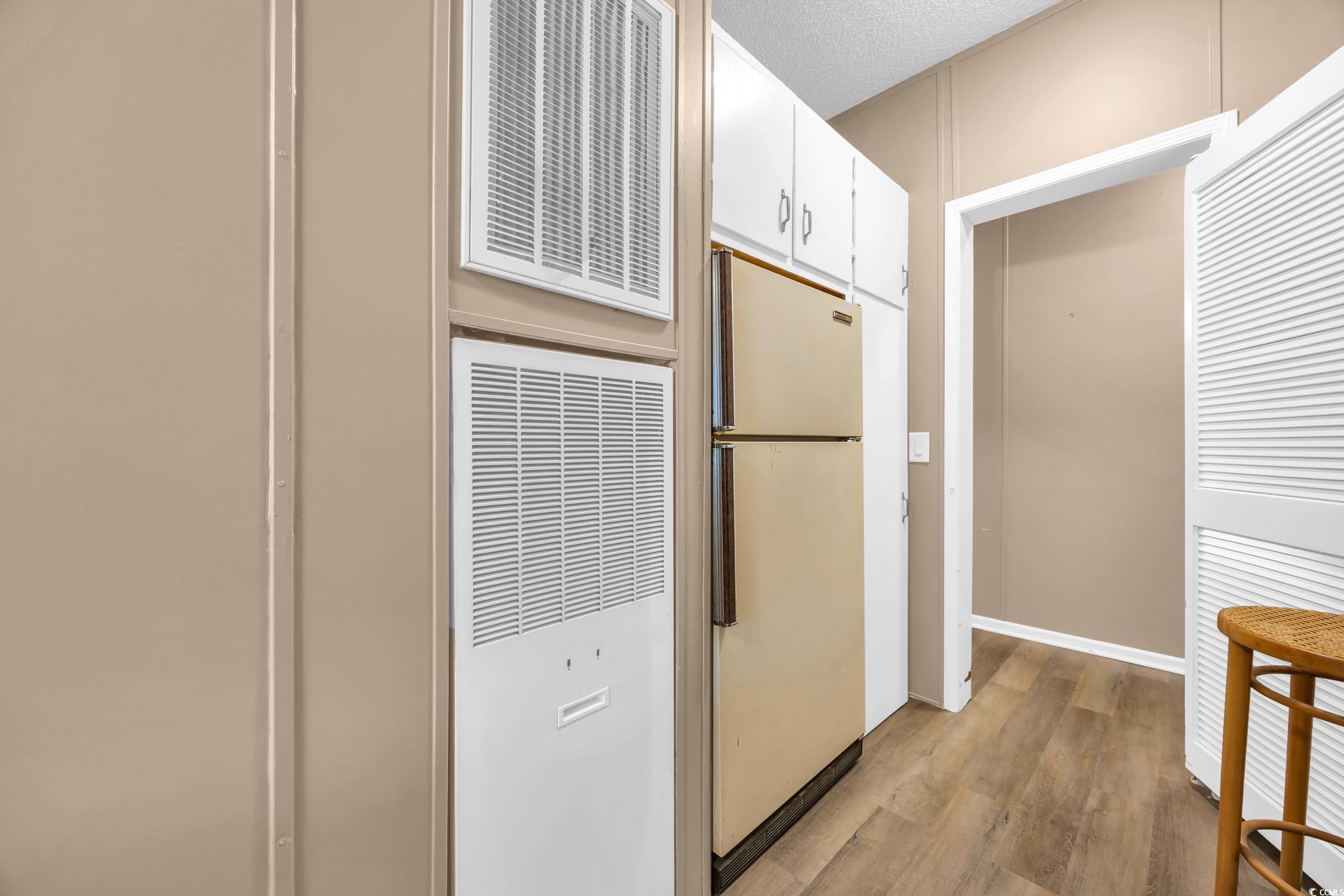 3373 Lake Pond Road Loris, SC 29569 - Photo 22 of 33 Kitchen featuring a heating unit, light wood-style flooring, freestanding refrigerator, white cabinets, and a textured ceiling