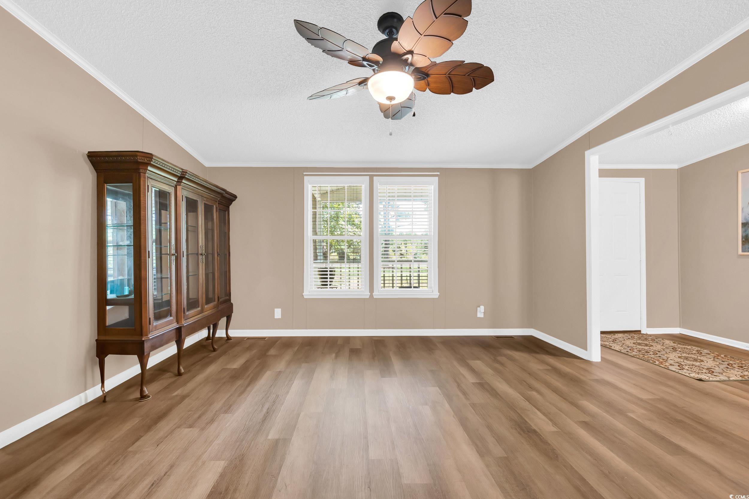 3373 Lake Pond Road Loris, SC 29569 - Photo 5 of 33 Unfurnished living room featuring crown molding, wood finished floors, ceiling fan, and a textured ceiling