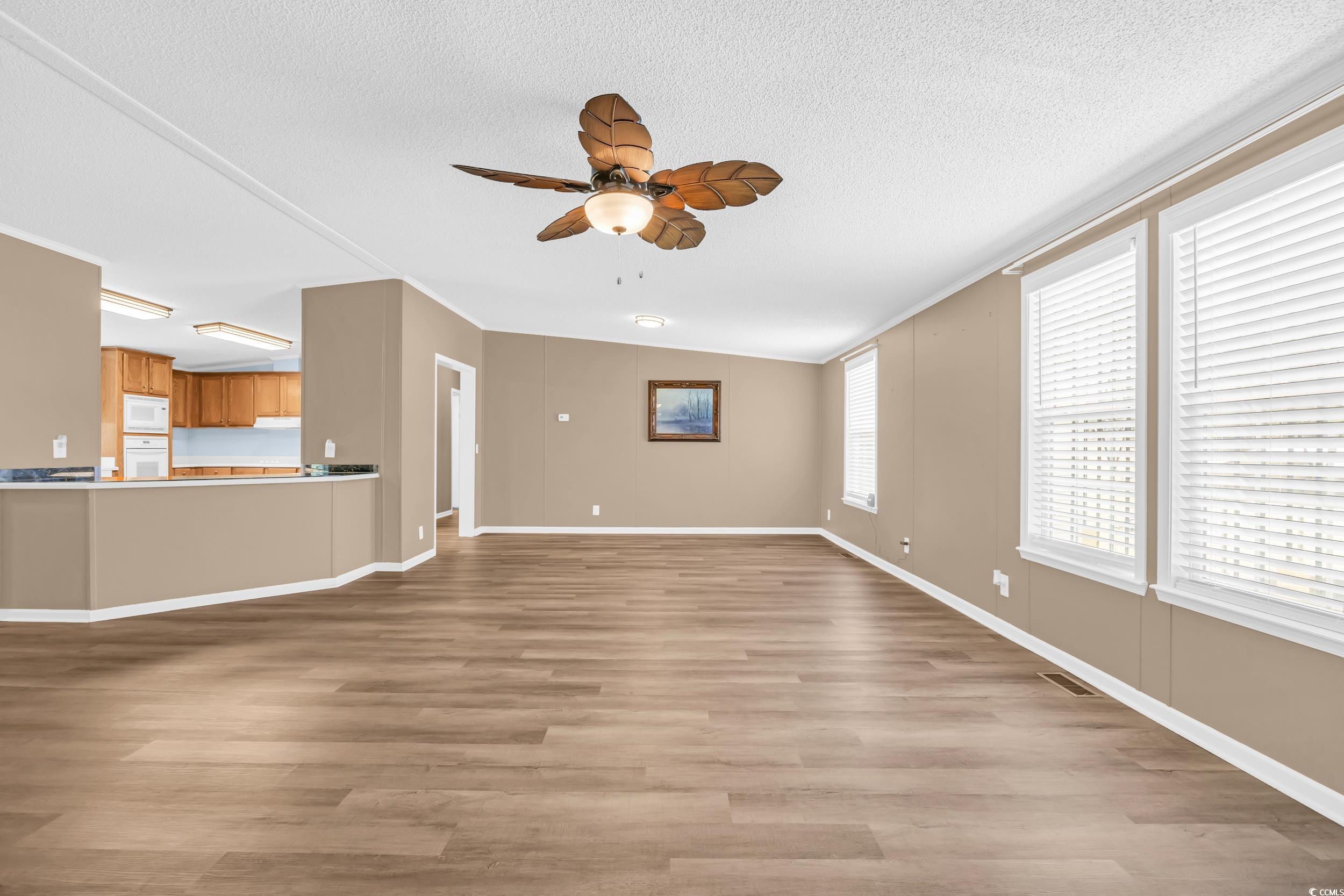 3373 Lake Pond Road Loris, SC 29569 - Photo 10 of 33 Unfurnished living room featuring ceiling fan, light wood-style floors, a textured ceiling, and ornamental molding
