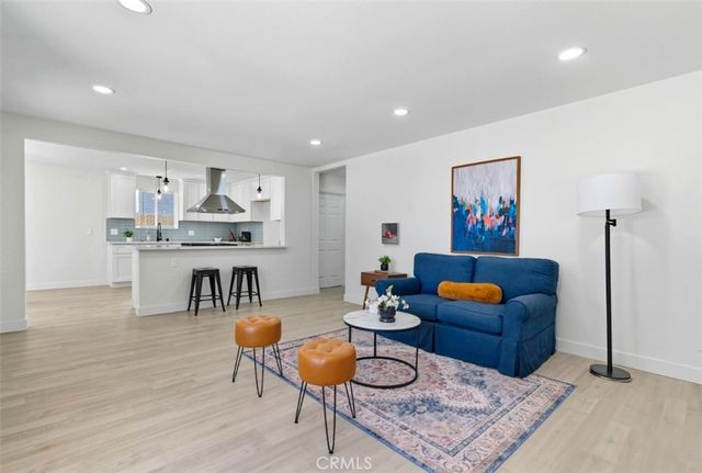a living room with furniture a rug and kitchen view