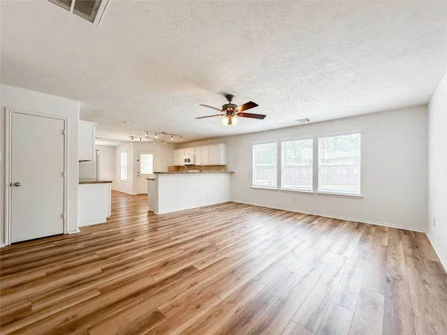 a view of empty room with wooden floor and window