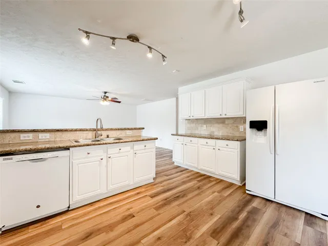 a kitchen with granite countertop white cabinets and white appliances
