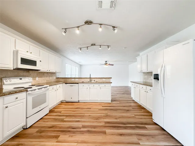 a large kitchen with cabinets wooden floor and stainless steel appliances