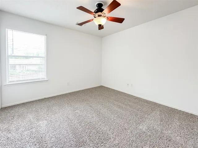 an empty room with windows and a ceiling fan