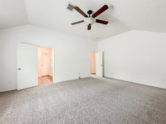 an empty room with ceiling fan and window