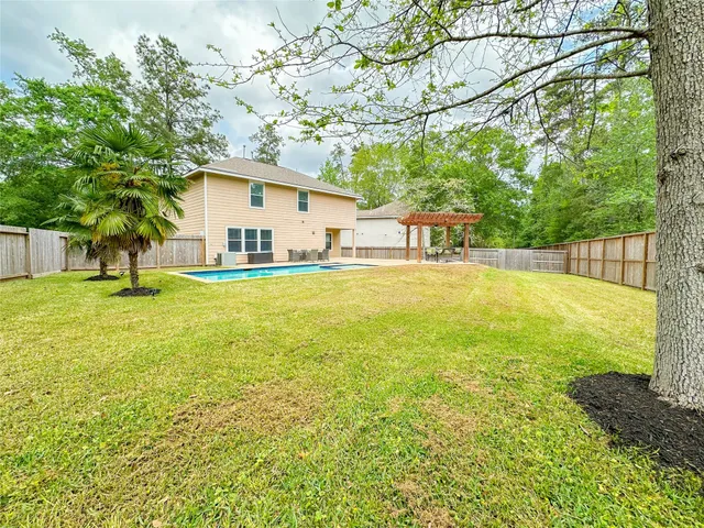 a view of a large pool with a yard and large trees