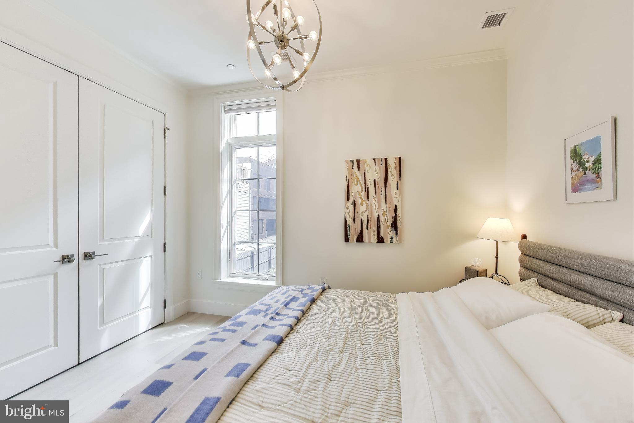 2122 N Street Northwest, Unit 5 Washington, DC 20037 - Photo 19 of 38 a bedroom with a large bed and a chandelier