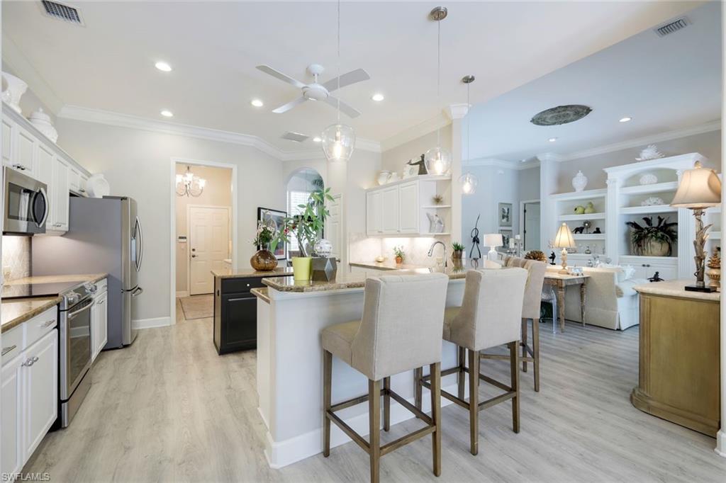 8475 Gleneagle Way Naples, FL 34120 - Photo 16 of 46 a kitchen with stainless steel appliances kitchen island granite countertop a table chairs sink and cabinets