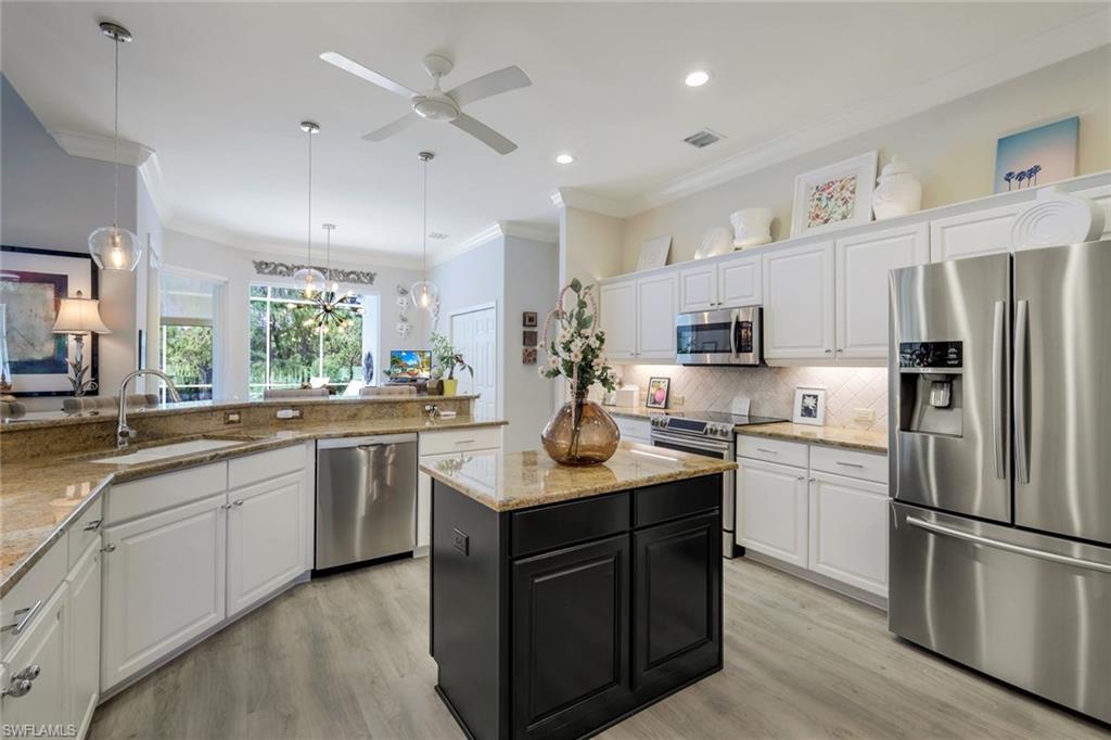 8475 Gleneagle Way Naples, FL 34120 - Photo 17 of 46 a kitchen with stainless steel appliances granite countertop a sink a stove a refrigerator and island with wooden floor