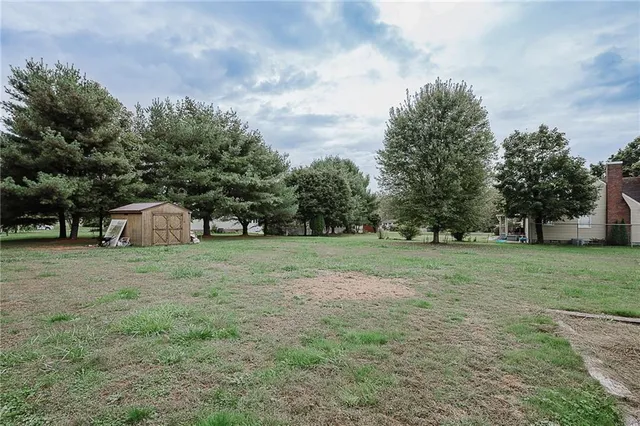 a view of a tiny house in a big yard with large trees