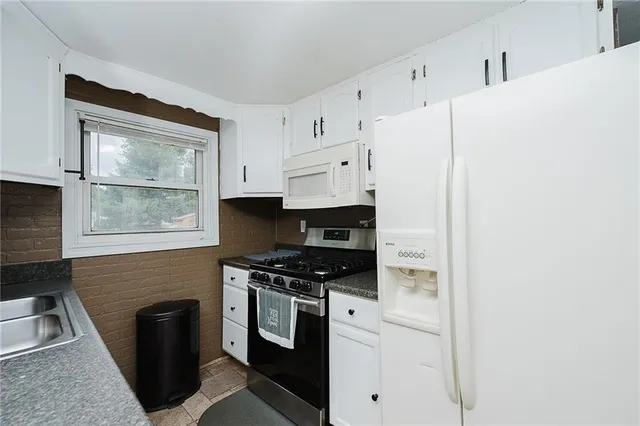 a kitchen with white cabinets and black appliances