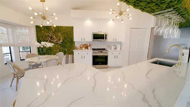 a large white kitchen with a refrigerator a stove a oven a dining table and chairs with wooden floor