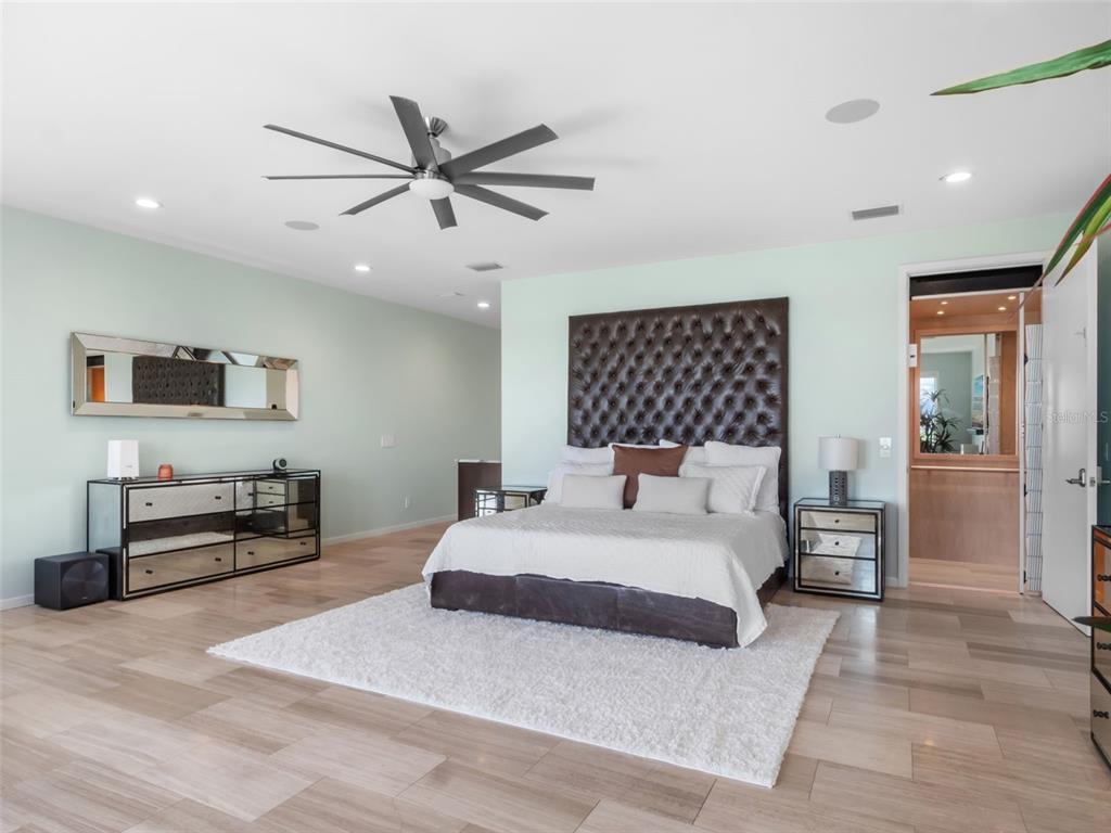1511 South Riverside Drive New Smyrna Beach, FL 32168 - Photo 40 of 81 a spacious bedroom with a bed a dresser and a chandelier