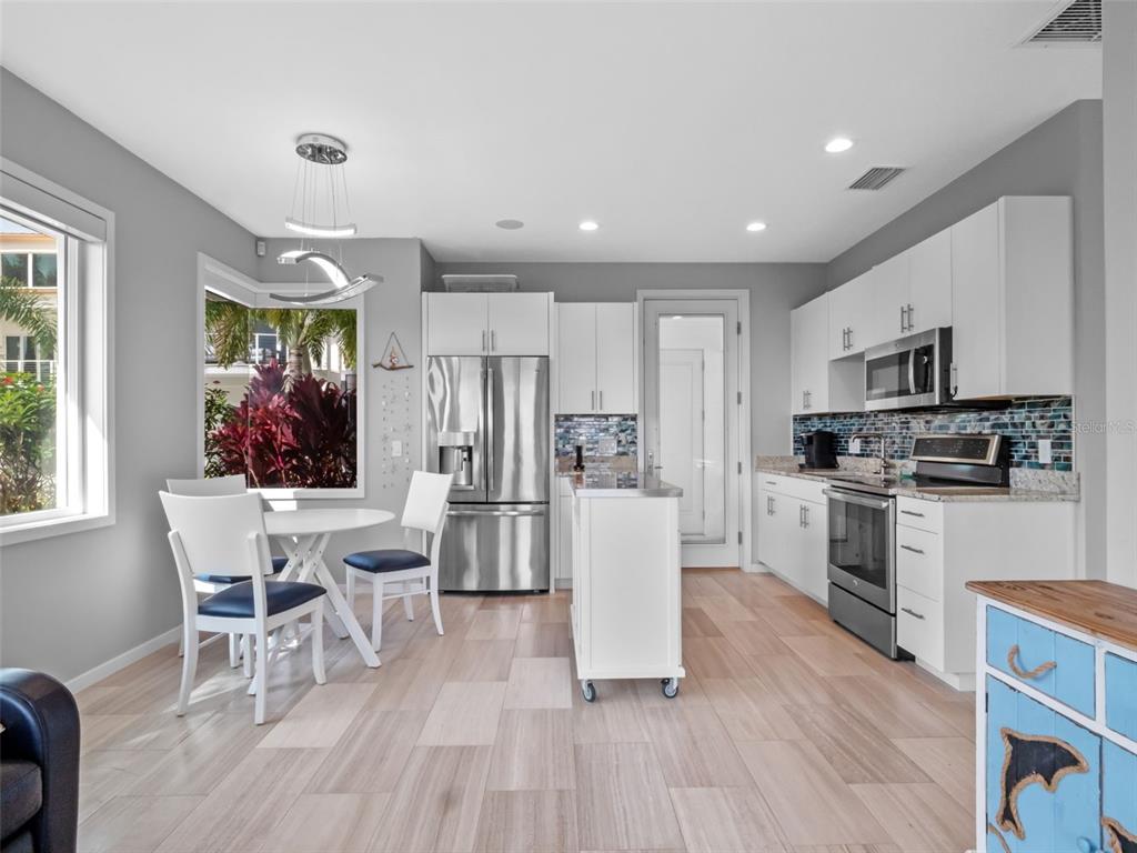 1511 South Riverside Drive New Smyrna Beach, FL 32168 - Photo 66 of 81 a kitchen with stainless steel appliances granite countertop a refrigerator a stove top oven a sink dishwasher a dining table and chairs with wooden floor