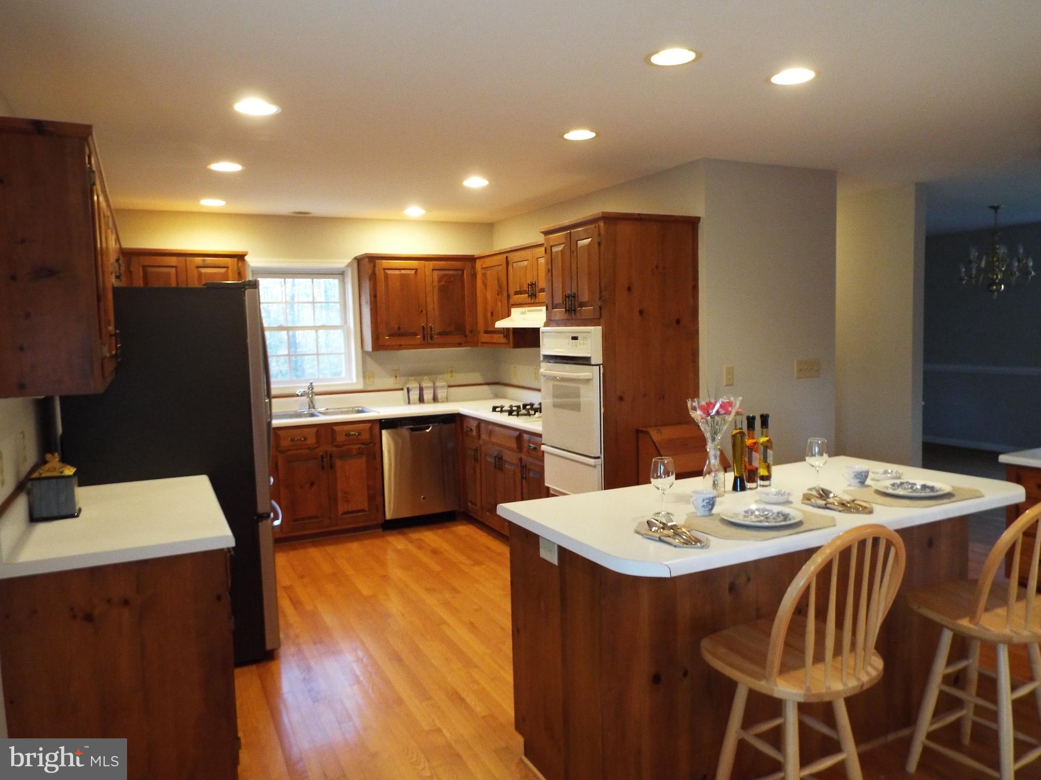 5545 Yanceyville Road Louisa, VA 23093 - Photo 55 of 64 a kitchen with stainless steel appliances kitchen island granite countertop a sink a stove a refrigerator with a dining table and chairs