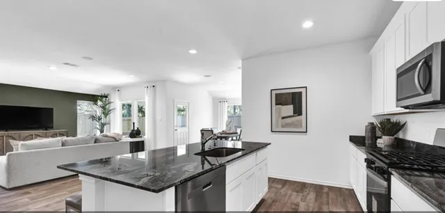 a kitchen with granite countertop a sink and a stove top oven with wooden floor