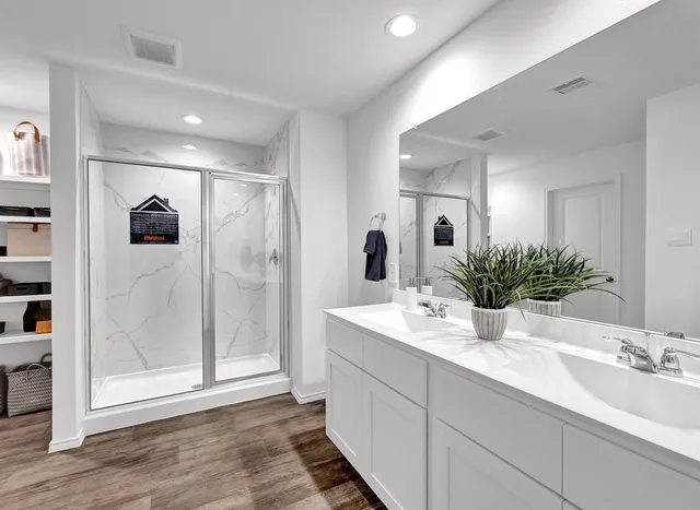 a bathroom with double vanity a mirror and shower