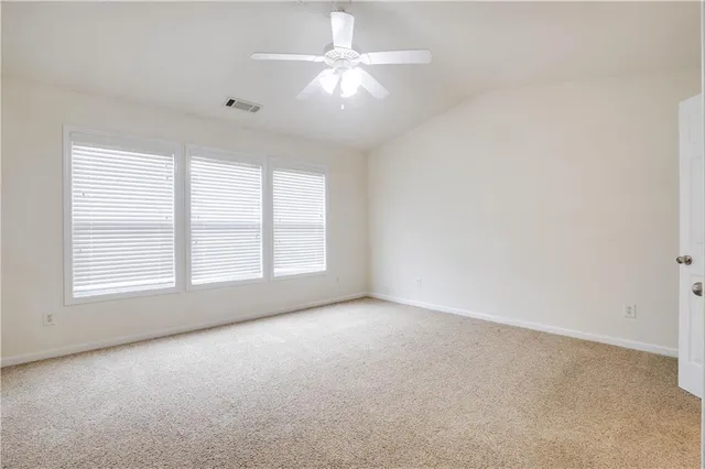 an empty room with windows and chandelier fan