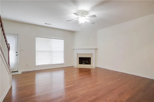 an empty room with wooden floor fireplace and windows