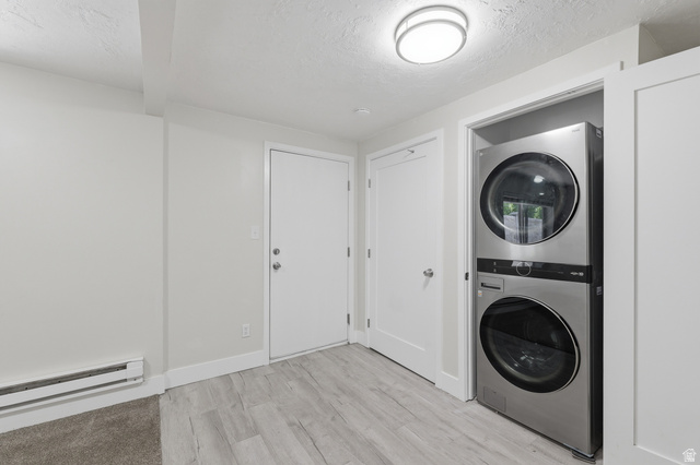831 Lennox Street, Unit 5 Midvale, UT 84047 - Photo 6 of 19 Laundry area featuring stacked washing machine and dryer, light wood finished floors, a textured ceiling, and a baseboard heating unit