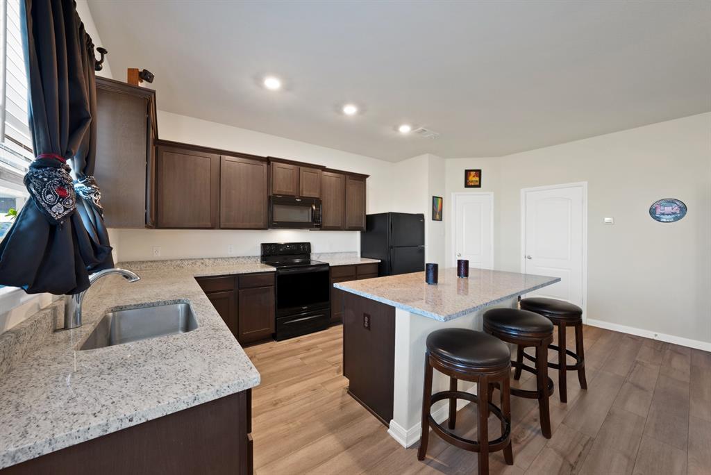 233 Lewis Lane Venus, TX 76084 - Photo 6 of 40 Modern kitchen with granite countertops, large center island, dark cabinetry, recessed lighting, and breakfast bar seating.
