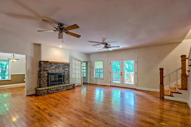 a view of an empty room with a window and wooden floor