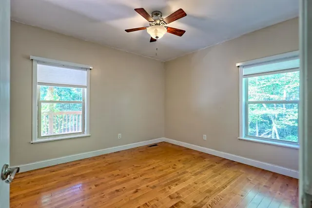 a view of a big room with wooden floor a chandelier fan and windows