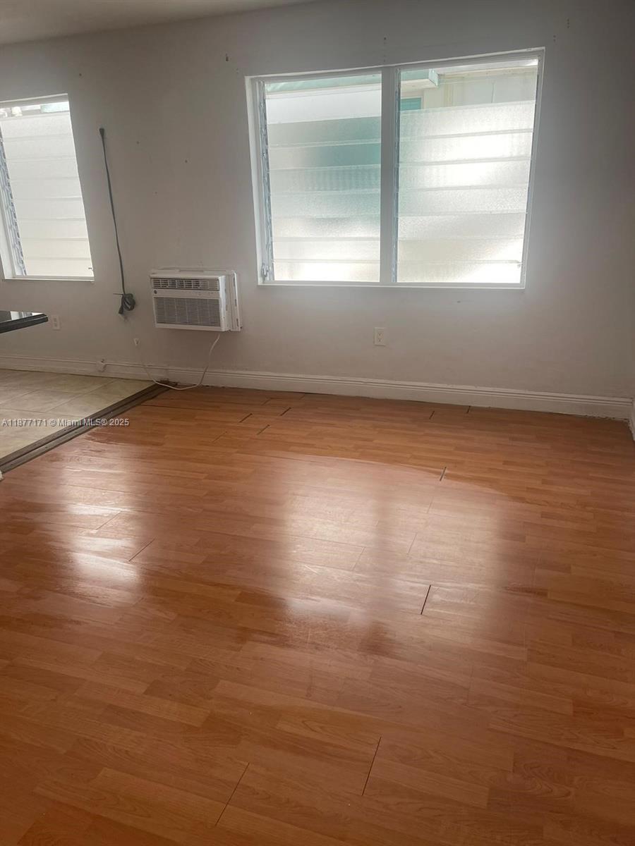 7928 Harding Avenue, Unit 1 Miami Beach, FL 33141 - Photo 13 of 17 an empty room with wooden floor and windows