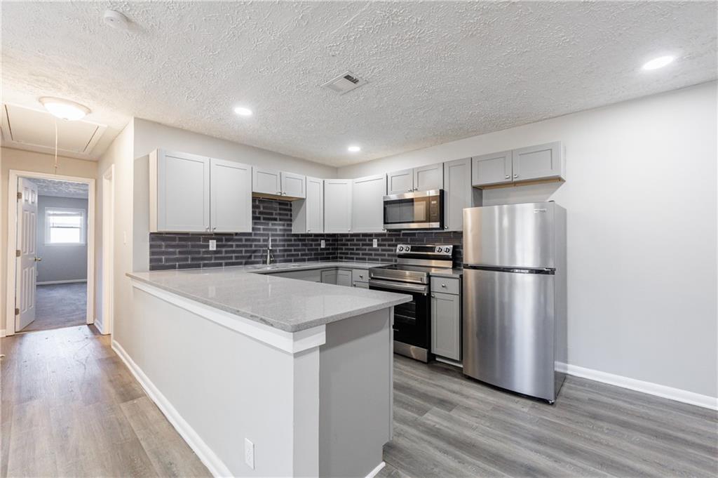 779 Amber Place Northwest Atlanta, GA 30331 - Photo 12 of 35 a kitchen with stainless steel appliances a refrigerator a stove a sink and white cabinets