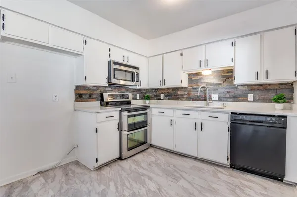 a kitchen with cabinets stainless steel appliances a sink and wooden floor
