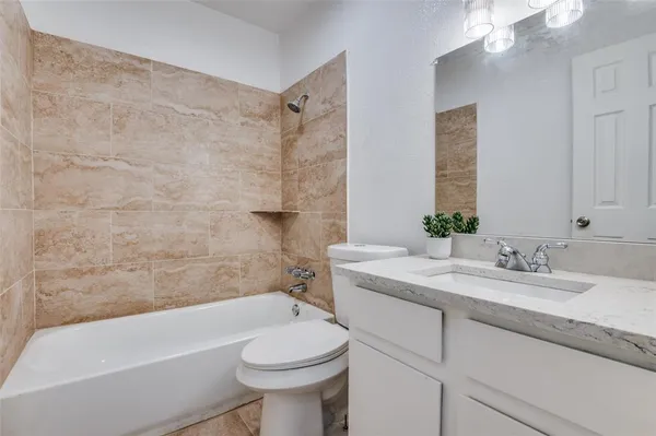 a bathroom with a granite countertop sink mirror vanity bathtub and toilet