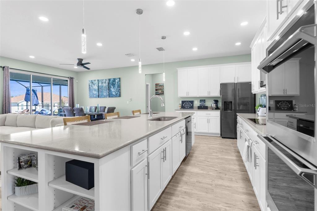 9347 North Star Court Weeki Wachee, FL 34613 - Photo 18 of 46 a large kitchen with stainless steel appliances kitchen island a large counter top a stove a chimney a sink and a refrigerator