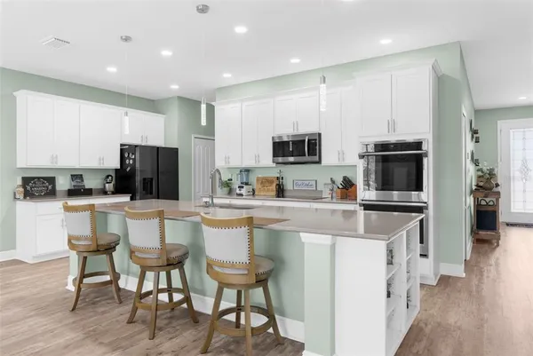 a kitchen with stainless steel appliances a stove a sink a microwave a refrigerator and cabinets